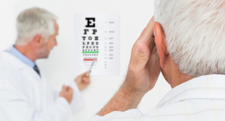 Pediatrician ophthalmologist with senior patient pointing at eye chart