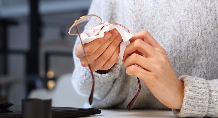 Cleaning glasses. The woman wipes her glasses with a cloth